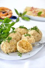 Deftige bayerische Semmelknödel mit Petersilie garniert, eine Breze und Sauerkraut im Hintergrund