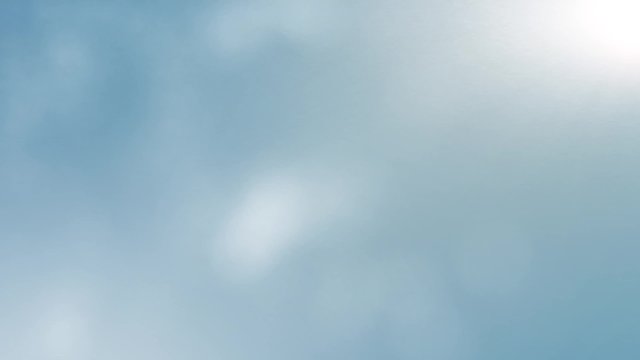 Looping background of bright blue sky with floating small clouds
