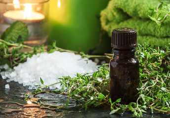 essential oil of thyme in the spa concept with sea salt, towels,