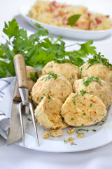 Deftige bayerische Semmelknödel mit Petersilie garniert, Sauerkraut mit Speck im Hintergrund