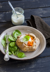 Savoury rustic pumpkin pie and fresh spinach on wood table. Delicious lunch, breakfast or snack