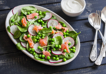 Smoked salmon, spinach, green pea and radish salad.  Delicious lunch. On a dark background