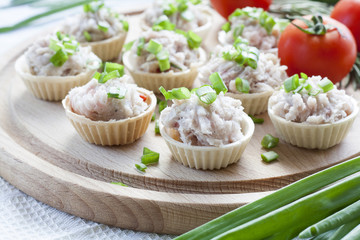 Tartlets with sowbelly  filling decorated with green onion on a wooden board