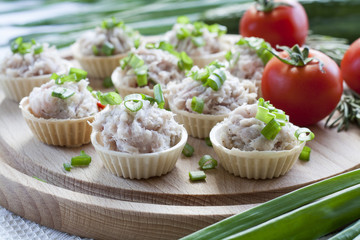 Tartlets with sowbelly  filling decorated with green onion on a wooden board