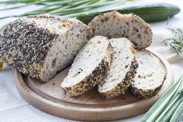 Sliced homemade bread loaf with sesame and other grains on a round desk at wooden table