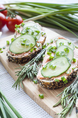 Sandwiches with fish butter, cucumber and herbs on wooden board for a snack breakfast