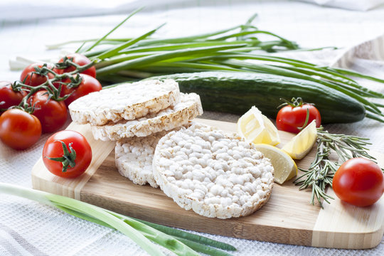 Plain rice cakes, galette rice with lemon, rosemary and vegetables on wooden board