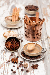 Cup of coffee and spices in a vintage silver cup on a wooden background