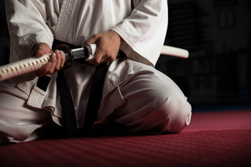 Close uo of young martial arts fighter with katana siting in seiza position