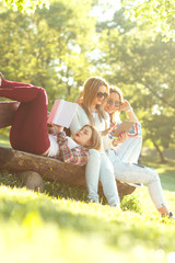 Fototapeta premium Three friends sitting on a park bench, chatting and enjoying the sunny day