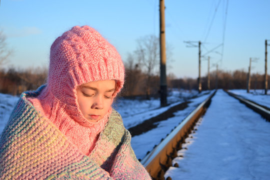 a little girl waiting for the train, little girl in knitted clothes