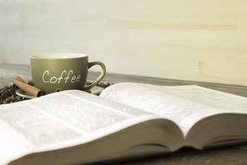 A cup of coffee with beans on the background of a  book. Focus on  the cup