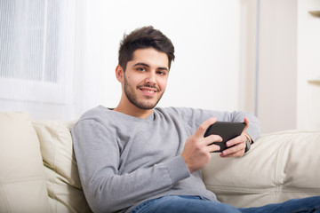 Handsome casual young man using a tablet at home