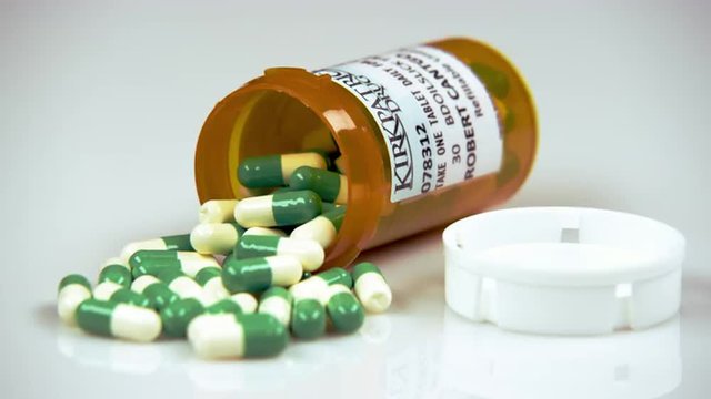Prescription bottle containing green and white pills.