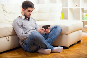 Handsome casual young man using a tablet at home