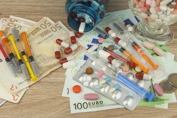 Money for expensive treatment. Money and pills. Pills of different colors on money. Genuine euro banknotes. Health financing.
