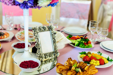 covered tables in pink color with a lot of tasty dishes and frame with the table number