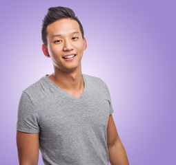 Handsome young asian man smiling wearing a grey shirt