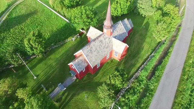 Aerial view of popular red wooden church contrasting with surrounding greenery in village Flakstad on Lofoten islands in Norway. Aerial 4k Ultra HD.