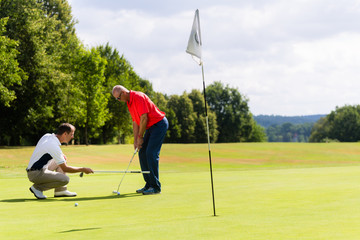 Senior man practicing golf with teacher helping