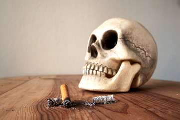 Close up of cigarette stub and blured  human skull