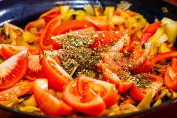 Cooking vegetable stew, tomatoes sprinkled with dried herbs.