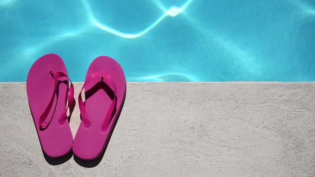 Pink slippers near swimming pool at poolside