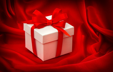 Gift box with bow ribbon on red silk