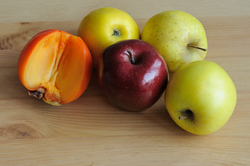 Apples with persimmon in wooden table