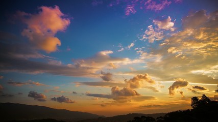 Very colorful day to night time lapse of clouds at sunset in the tropic. The sun flashes all around during the setting and city lights showoff at night