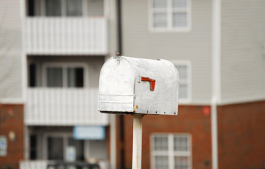 close up on old fashioned mailbox in residential area with blurred building as background