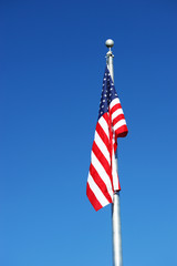 American flag on the pole against blue sky, no wind or waving