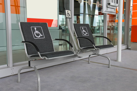 Two seats for people with disabilities in modern airport hall.