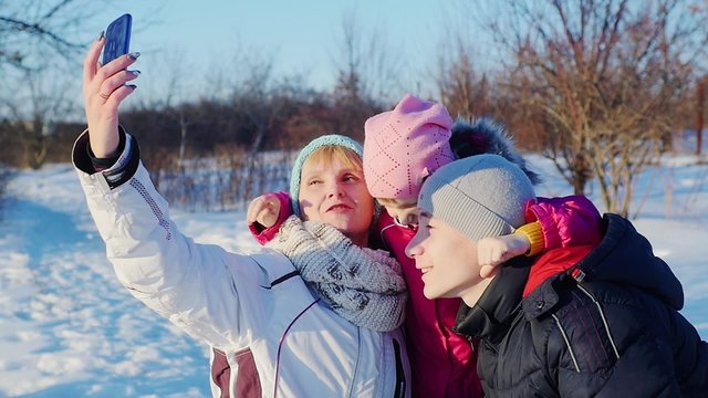 Woman do selfie with two children in the winter park