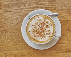Cappuccino in white cup close-up on wood background