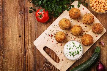 Chickpea falafel balls on a wooden desk with vegetables