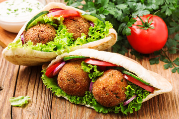 Falafel and fresh vegetables in pita bread on wooden table