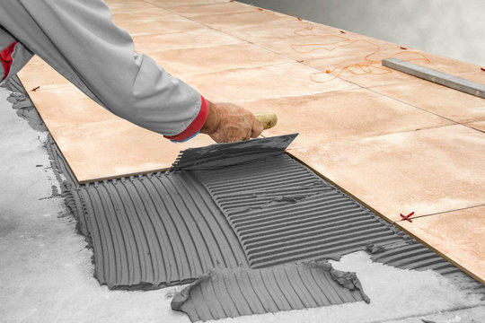 Home improvement, renovation - construction worker tiler is tiling, ceramic tile floor adhesive