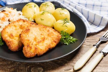 Fried pork chop in breadcrumbs, served with boiled potatoes and
