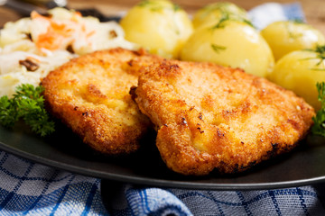 Fried pork chop in breadcrumbs, served with boiled potatoes and