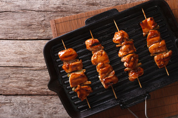 yakitori skewers of chicken on a grill pan. Horizontal top view
