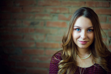 Naklejka premium A young female fashion model in dress against a brick wall background. She is looking at.
