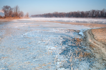 Frozen bank of a misty river in early morning