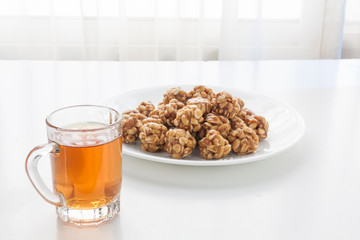 Sweet peanut balls in a plate and glass of black tea