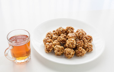 Sweet peanut balls in a plate and glass of black tea