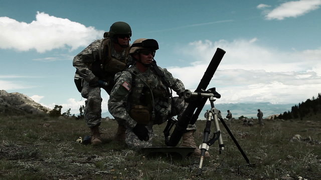 Instructor teaching soldier on mortar range about aiming mortar launcher.