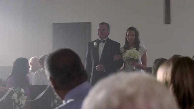 Bride seeming hesitant as she is escorted down the aisle.