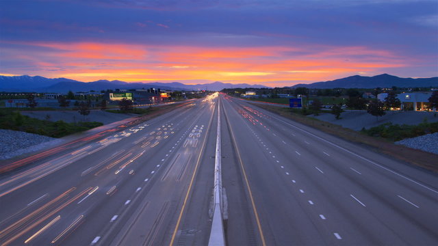 Time-lapse high energy shot of traffic on a highway from overpass at sunset
