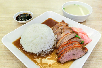 Roasted Duck and Red Pork with Rice on White Square Plate Served with Sauce and Soup on Wooden Table