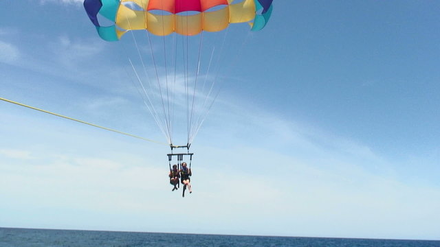 Two Girls Descending To The Water In A Parasail.